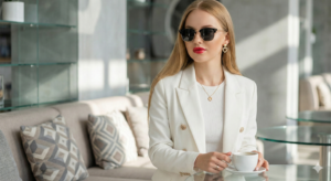 blonde woman in white blazer sitting at luxurious cafe holding coffee cup